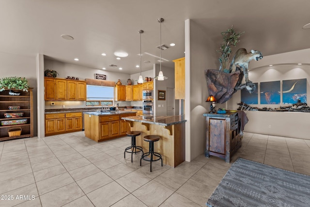 20910 W Cattle Iron Dr, Wickenburg, AZ 85390 - kitchen with a breakfast bar, brown cabinets, dark stone counters, a kitchen island, and appliances with stainless steel finishes