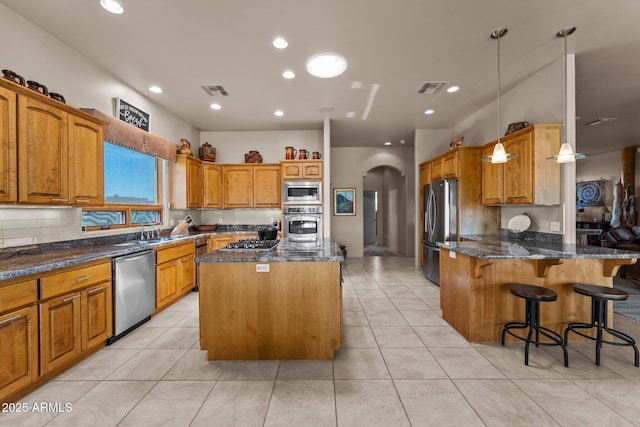 20910 W Cattle Iron Dr, Wickenburg, AZ 85390 - kitchen featuring a kitchen island, dark stone countertops, stainless steel appliances, visible vents, and arched walkways