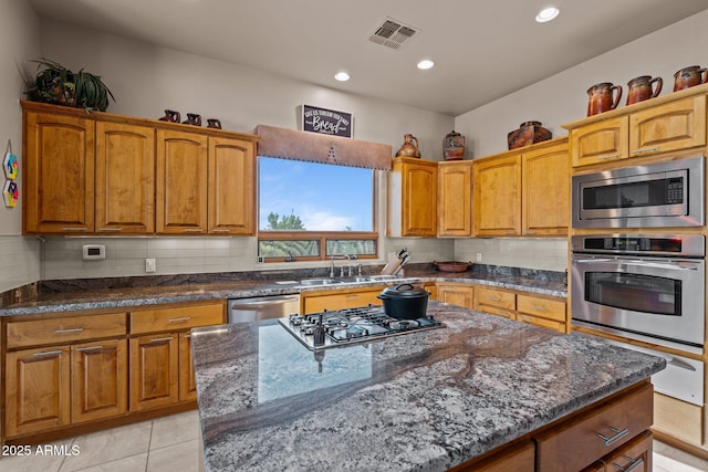 20910 W Cattle Iron Dr, Wickenburg, AZ 85390 - kitchen featuring stainless steel appliances, dark stone counters, backsplash, a sink, and visible vents