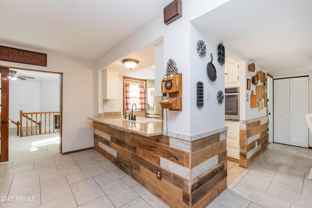 kitchen featuring sink, appliances with stainless steel finishes, white cabinets, light tile patterned flooring, and kitchen peninsula