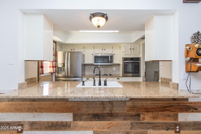 kitchen with cream cabinets, sink, backsplash, stainless steel appliances, and light stone countertops