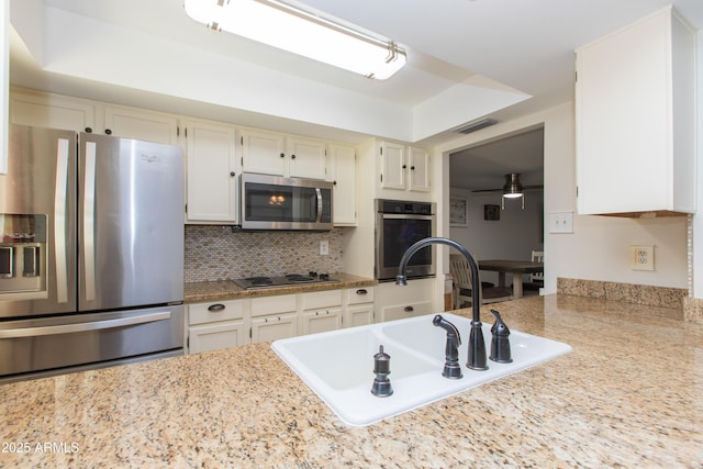 kitchen with sink, ceiling fan, white cabinetry, stainless steel appliances, and decorative backsplash