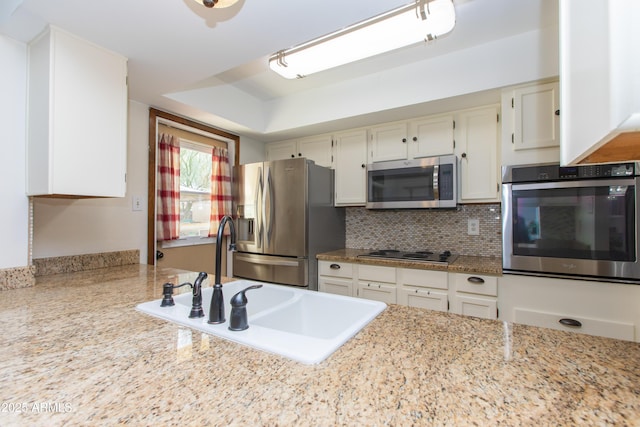 kitchen with tasteful backsplash, white cabinetry, appliances with stainless steel finishes, and sink