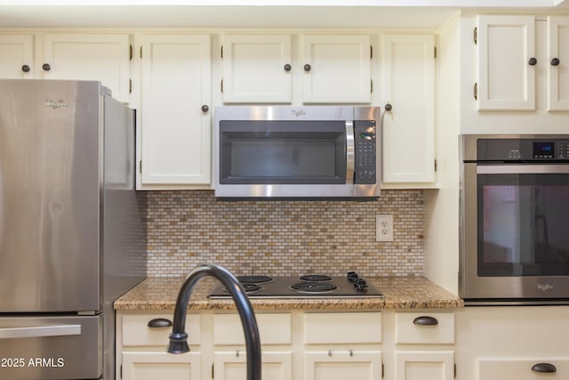 kitchen with white cabinetry, appliances with stainless steel finishes, light stone countertops, and backsplash