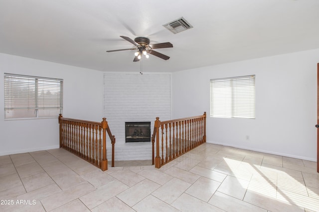 interior space featuring ceiling fan, a brick fireplace, and light tile patterned floors