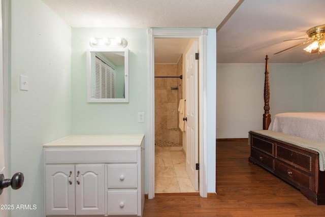 bathroom featuring crown molding, vanity, hardwood / wood-style flooring, and ceiling fan