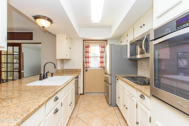 kitchen featuring sink, backsplash, stainless steel appliances, a tray ceiling, and white cabinets