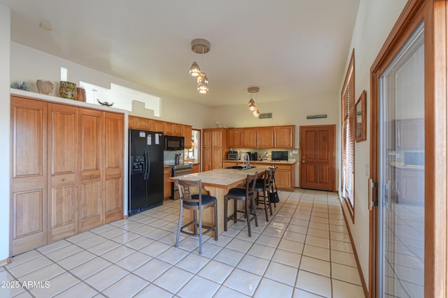 kitchen featuring light tile patterned floors, sink, black appliances, decorative backsplash, and decorative light fixtures