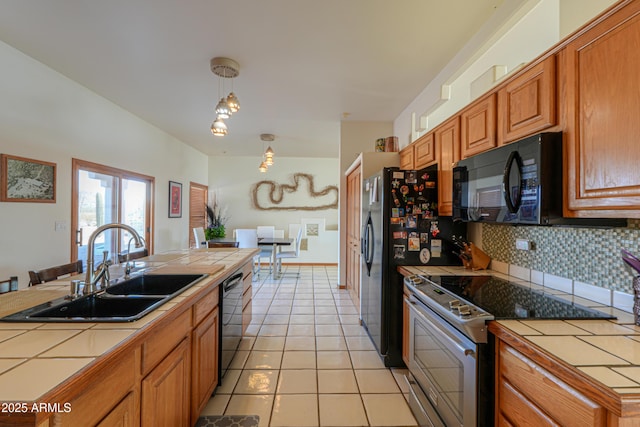 kitchen with sink, tile countertops, decorative light fixtures, black appliances, and backsplash