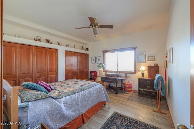 bedroom featuring ceiling fan, light hardwood / wood-style floors, and two closets