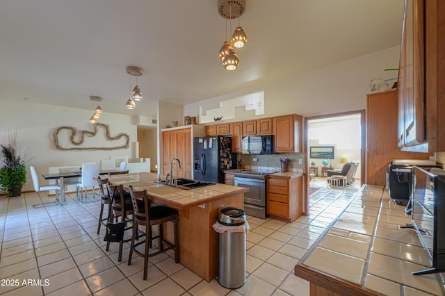 kitchen with pendant lighting, tile countertops, sink, and black appliances