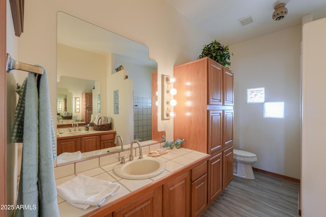 bathroom with hardwood / wood-style flooring, vanity, a shower, and toilet