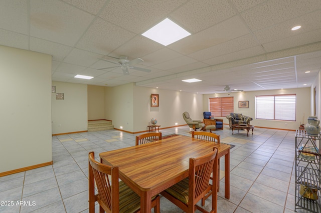 tiled dining area with ceiling fan and a paneled ceiling