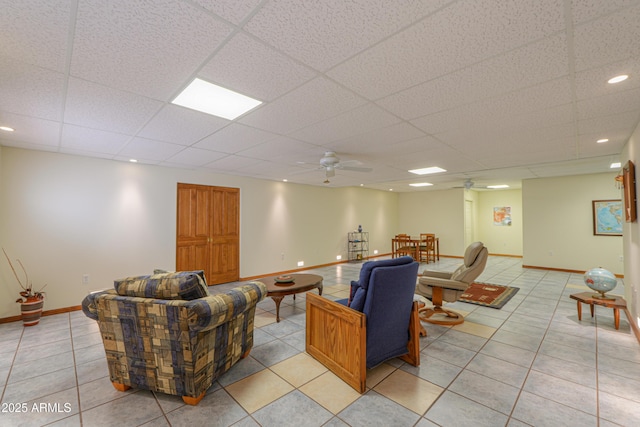 living room featuring light tile patterned floors, a drop ceiling, and ceiling fan