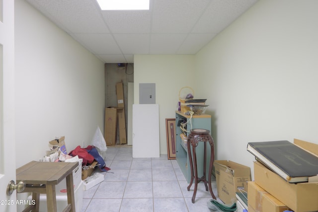 interior space with light tile patterned flooring, a drop ceiling, and electric panel