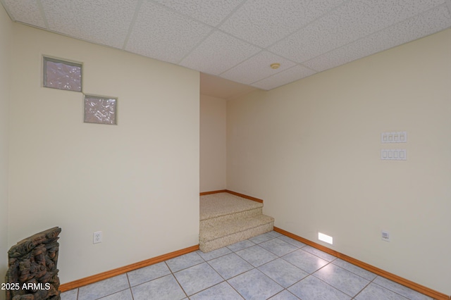 empty room featuring a paneled ceiling and light tile patterned floors