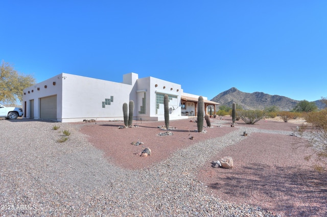 pueblo-style home featuring a garage and a mountain view