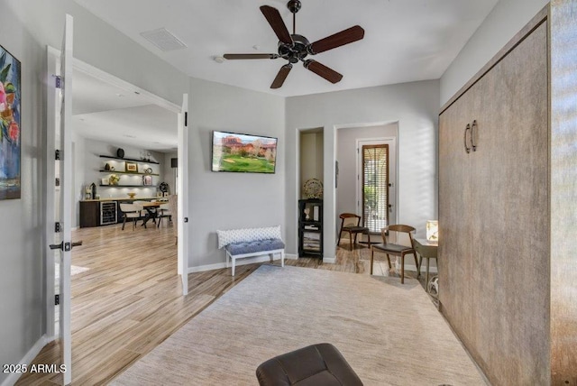 sitting room featuring light wood finished floors, visible vents, baseboards, and ceiling fan