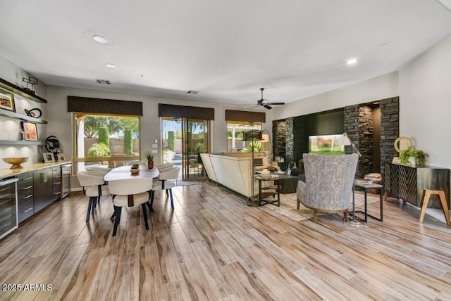 dining area featuring light wood-style flooring, a ceiling fan, and visible vents