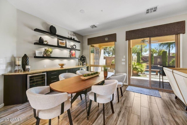 dining room with visible vents, a dry bar, beverage cooler, and light wood-style floors