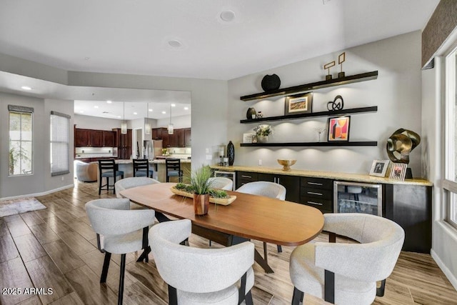 dining room with light wood-style flooring, recessed lighting, baseboards, and wine cooler