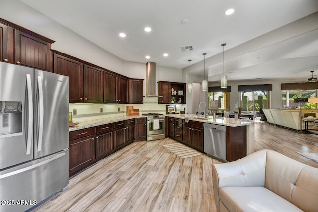 kitchen with visible vents, a peninsula, appliances with stainless steel finishes, wall chimney exhaust hood, and open floor plan