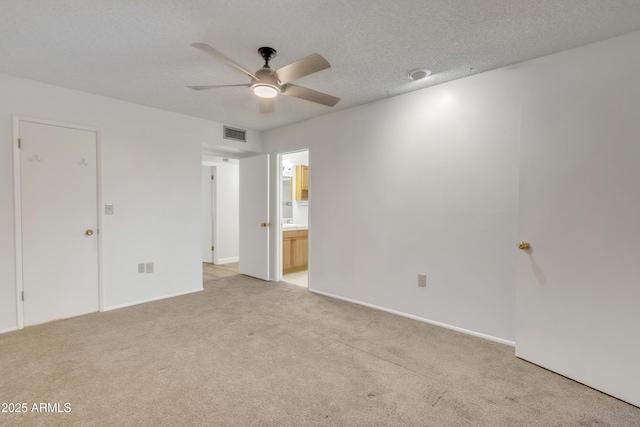 empty room featuring a textured ceiling, ceiling fan, visible vents, and light colored carpet