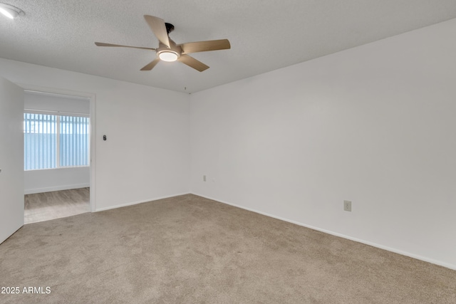carpeted empty room with a textured ceiling, baseboards, and ceiling fan