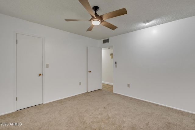 interior space with baseboards, a textured ceiling, carpet floors, ceiling fan, and visible vents