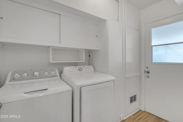 laundry area featuring separate washer and dryer, light wood finished floors, laundry area, and visible vents