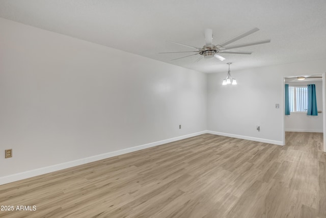 spare room with baseboards, light wood-style floors, and ceiling fan with notable chandelier
