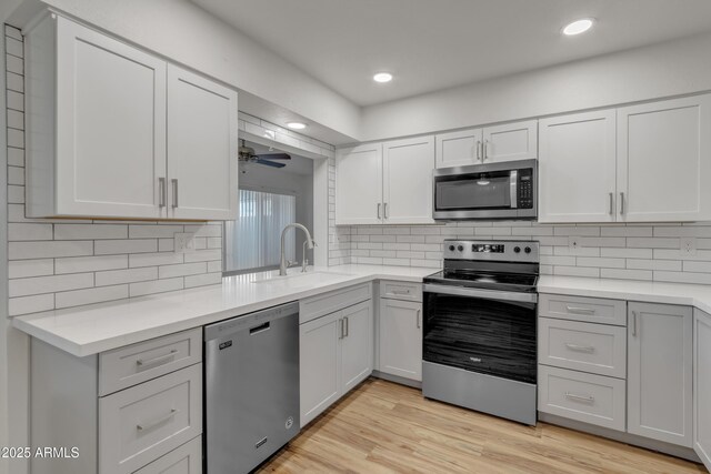 kitchen featuring light countertops, a sink, stainless steel appliances, and light wood-style floors