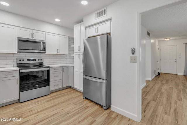 kitchen with visible vents, stainless steel appliances, backsplash, and light wood-type flooring