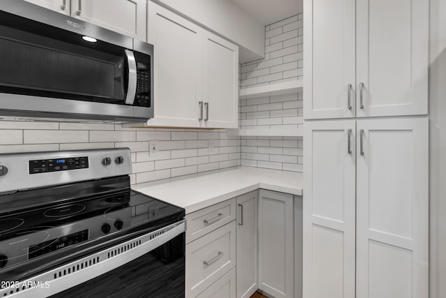 kitchen featuring decorative backsplash, light countertops, white cabinets, appliances with stainless steel finishes, and open shelves