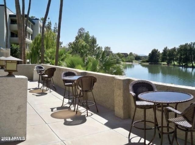 balcony with a patio area, a bar, and a water view