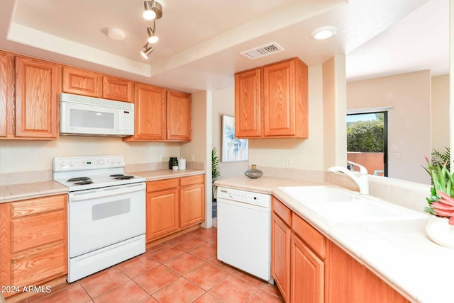 kitchen with white appliances, tile counters, a raised ceiling, light tile patterned floors, and sink