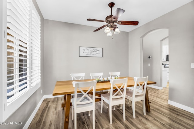 18822 E Flintlock Dr, Queen Creek, AZ 85142 - dining space with arched walkways, baseboards, ceiling fan, and light wood-style flooring
