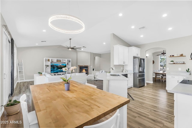 18822 E Flintlock Dr, Queen Creek, AZ 85142 - dining area with visible vents, a glass covered fireplace, a ceiling fan, light wood-style flooring, and vaulted ceiling