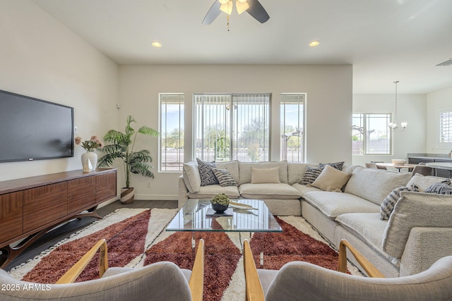 living area featuring wood finished floors, visible vents, baseboards, recessed lighting, and ceiling fan with notable chandelier