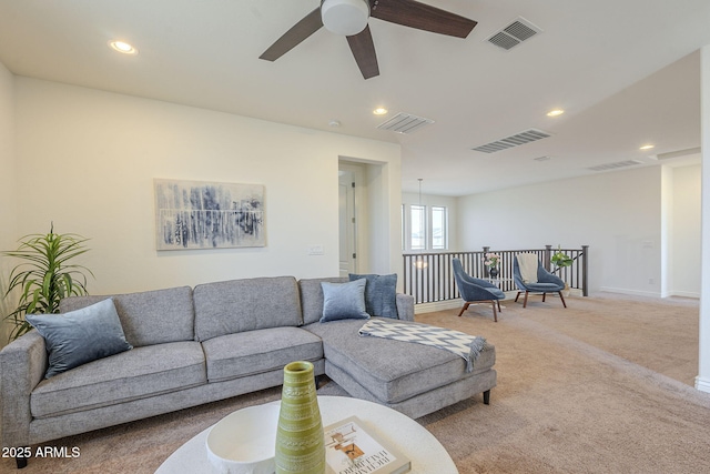 living area with light carpet, visible vents, and ceiling fan