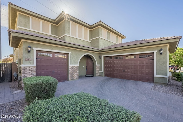 view of front of house featuring brick siding, stucco siding, and decorative driveway