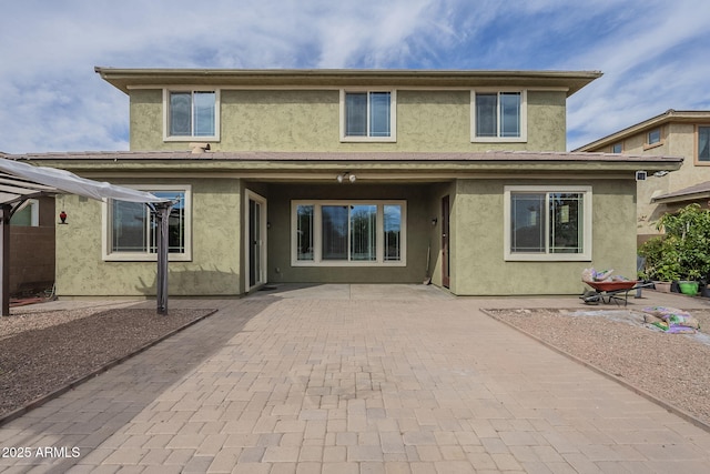 rear view of house with a patio and stucco siding