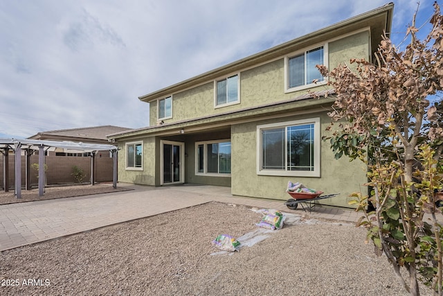 rear view of property featuring a patio area, stucco siding, a pergola, and fence