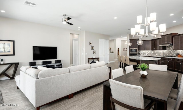 dining space featuring ceiling fan with notable chandelier and sink