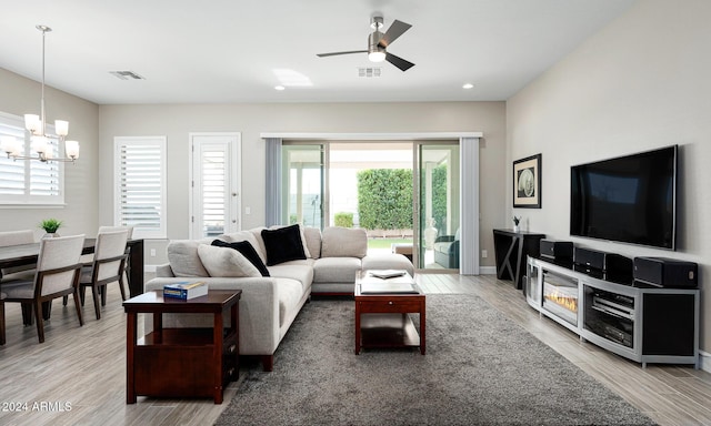 living room with ceiling fan with notable chandelier