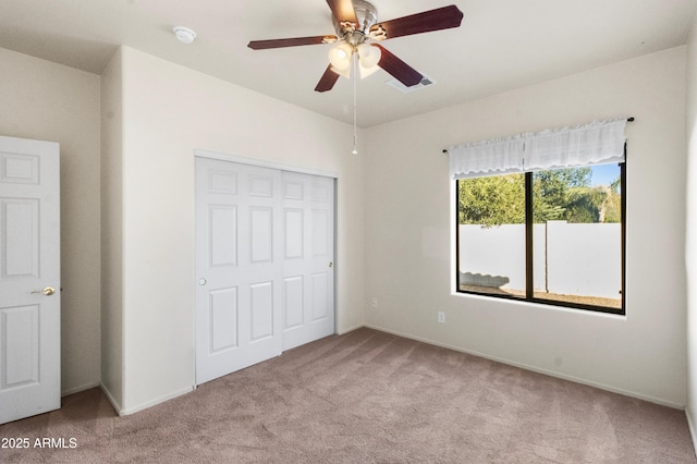 unfurnished bedroom featuring a closet, light colored carpet, and ceiling fan