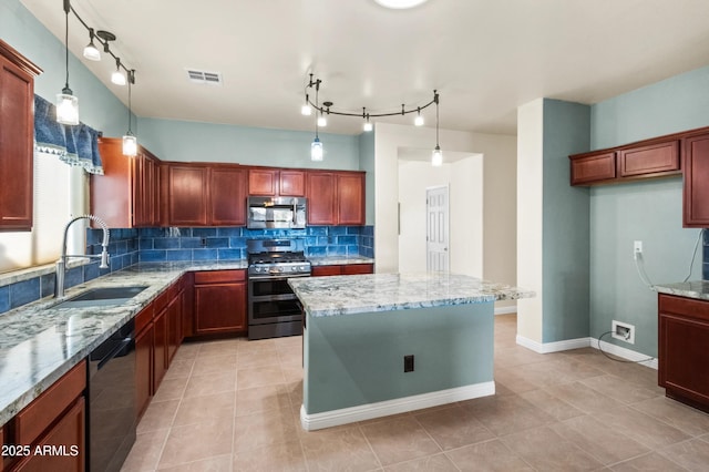 kitchen featuring appliances with stainless steel finishes, light stone counters, hanging light fixtures, and sink