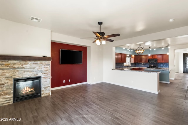 unfurnished living room featuring a fireplace, sink, ceiling fan with notable chandelier, and dark hardwood / wood-style floors