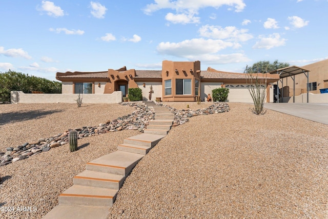 pueblo revival-style home with a garage and a carport