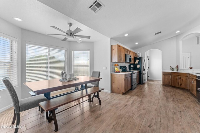 dining area featuring light wood-type flooring, a textured ceiling, ceiling fan, and lofted ceiling